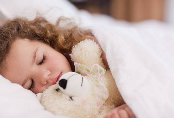 Flicka som sover med en leksak