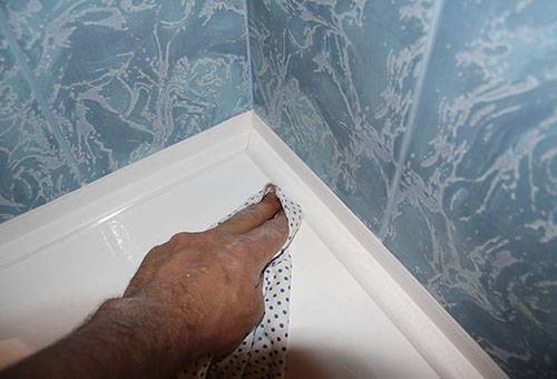 Tinatanggal ang labis na silicone sealant mula sa bathtub