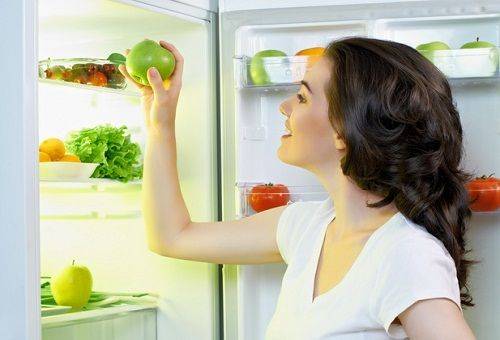 meisje met een appel bij de koelkast