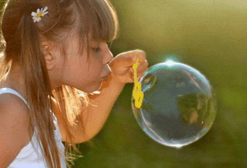 klein meisje blaast een zeepbel op