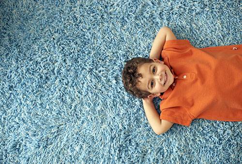 Pojken ligger på en ren matta