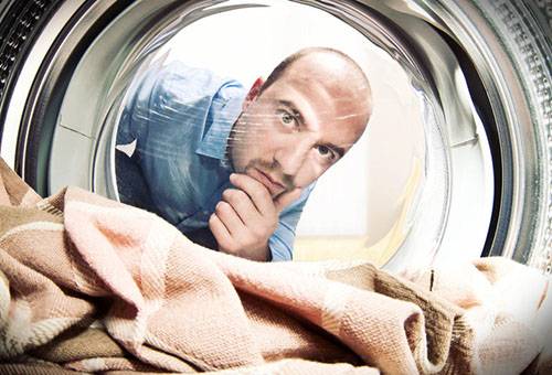 Vyras stebi skalbimą skalbimo mašinoje