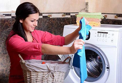 Kadın çamaşırları çamaşır makinesinden çeker.