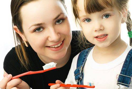 vrouw met een meisje met tandenborstels in de hand