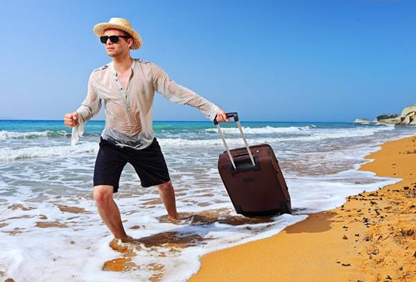 Man på stranden med en resväska