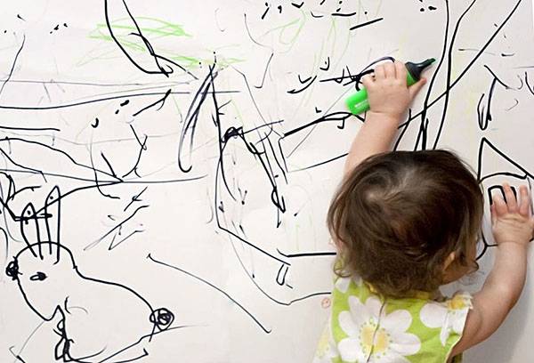 يرسم الطفل على جدار أبيض