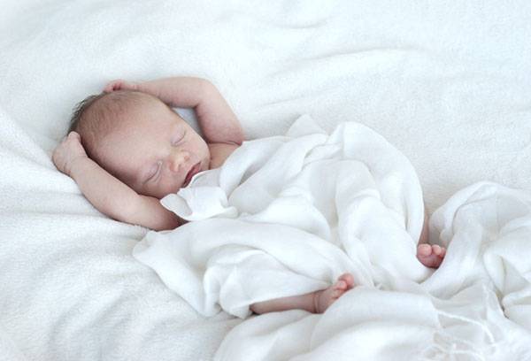 Hafif bir battaniyenin altında uyuyan bebek