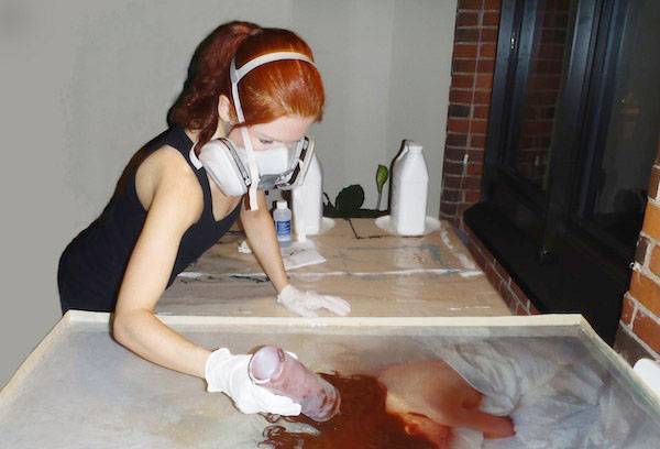 Een meisje in een gasmasker werkt met epoxy