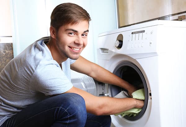 En mann tar ut klesvask fra en vaskemaskin