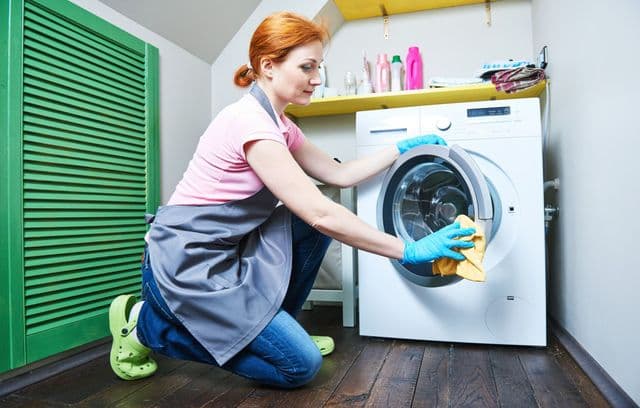 La ragazza pulisce una lavatrice