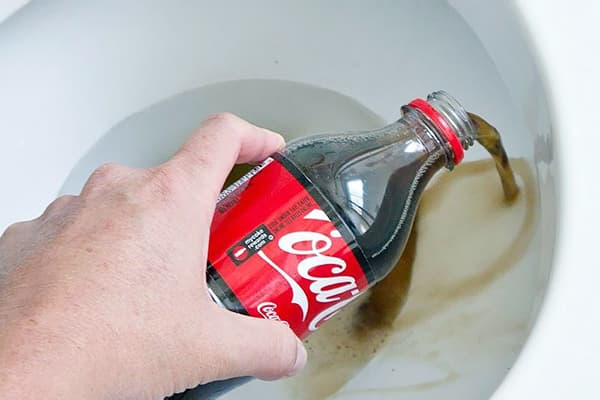 En mann skjenker Coca-Cola på toalettet