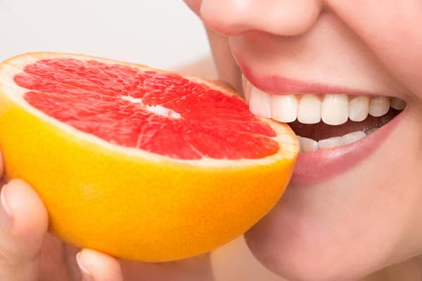 Kvinna som äter grapefrukt