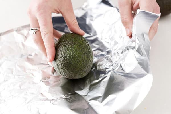 Vrouw wikkelt avocado in folie