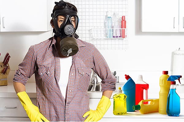 Žena v plynovej maske vedľa domácich chemikálií