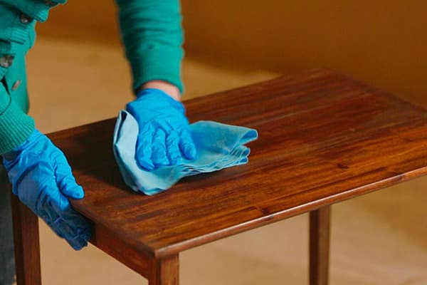 Bearbetar ett träbord med möbelvax