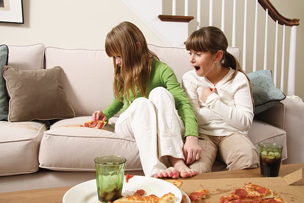 Girl menjatuhkan sepotong pizza di atas sofa