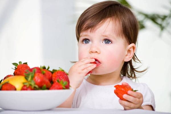 Copil care mănâncă căpșuni