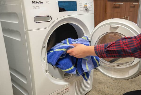 laddar tvätt i maskinen