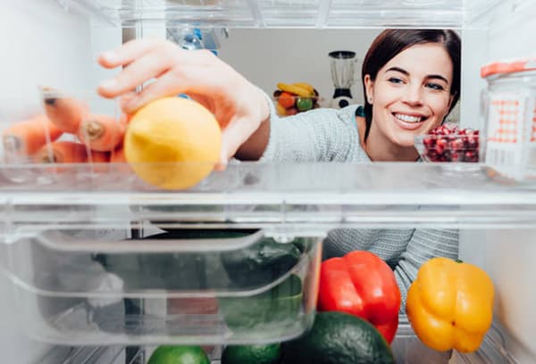 Mädchen legt Zitrone in den Kühlschrank