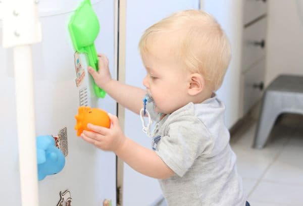 Leker barn ved kjøleskapet