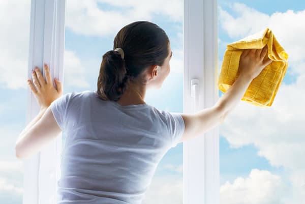 Žena myje okno za slunečného počasí
