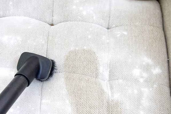 Netejar el sofà amb un refresc i una aspiradora