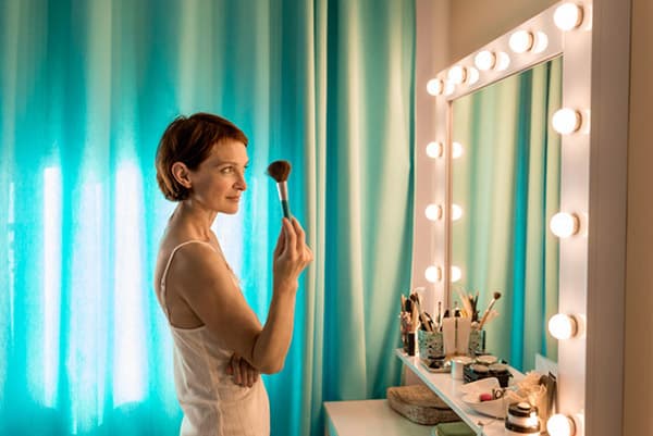 Mulher coloca maquiagem na frente de um espelho