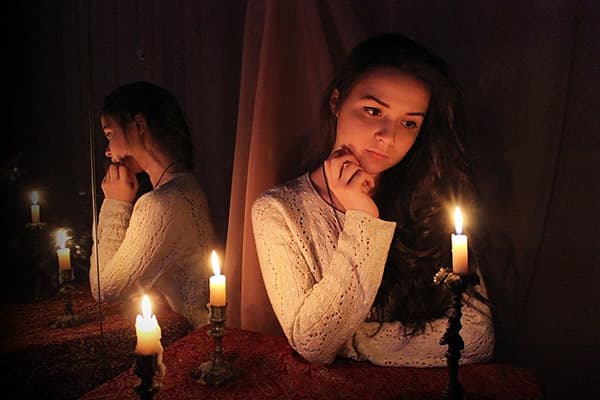 Menina sentada no espelho com velas