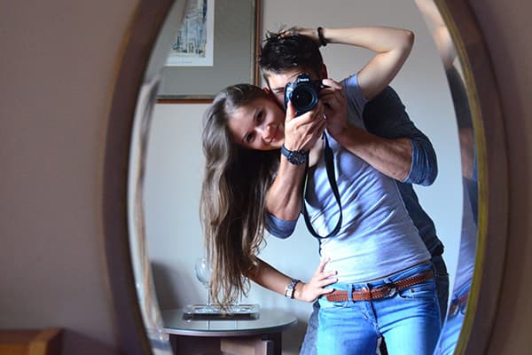 Jovem casal tirando fotos na frente de um espelho