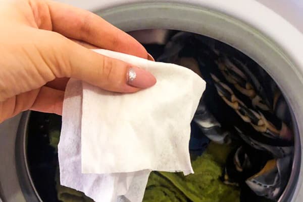 Kvinne legger et vått håndkle i en vaskemaskin
