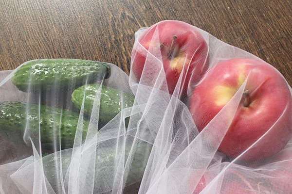 Pepinos e maçãs em sacos ecológicos
