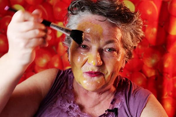 Uma mulher idosa coloca uma máscara de ovo no rosto