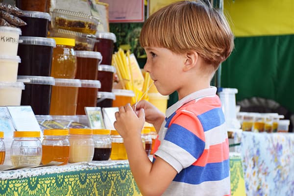 Момче вкусва мед на панаира